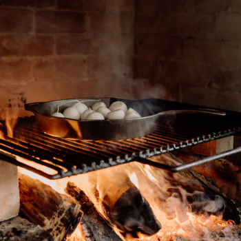 Ironclad Cast Iron Legacy Pan 28cm frying turnips on an open fire grill.