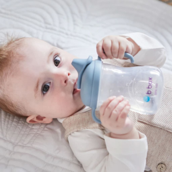 Lifestyle B.Box Spout Cup 240ml held by a baby in bed.