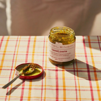 Ottolenghi Hawaij Paste open jar on a tartan pattern table.