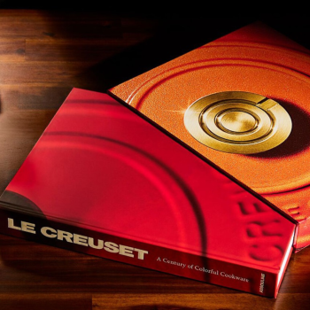 Le Creuset Book by Assouline on a wooden table.