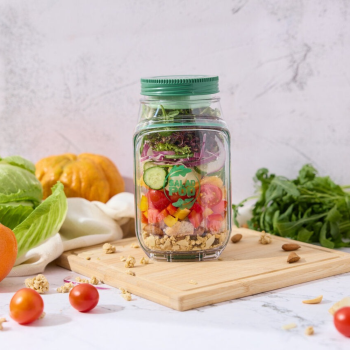 Prepara Salad Pod filled with chicken and veges on a chopping board sorrounded by its filling.